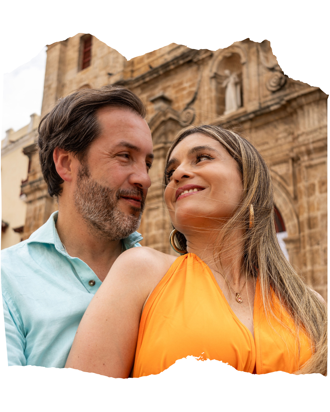 Carol y Carlos mirándose frente a una iglesia de piedra