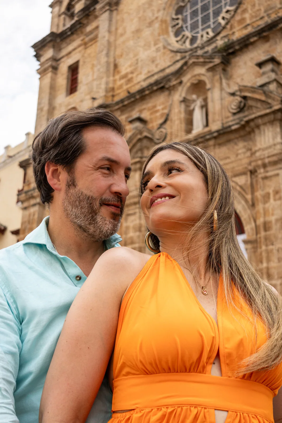 Carol y Carlos mirándose frente a una iglesia colonial de Cartagena